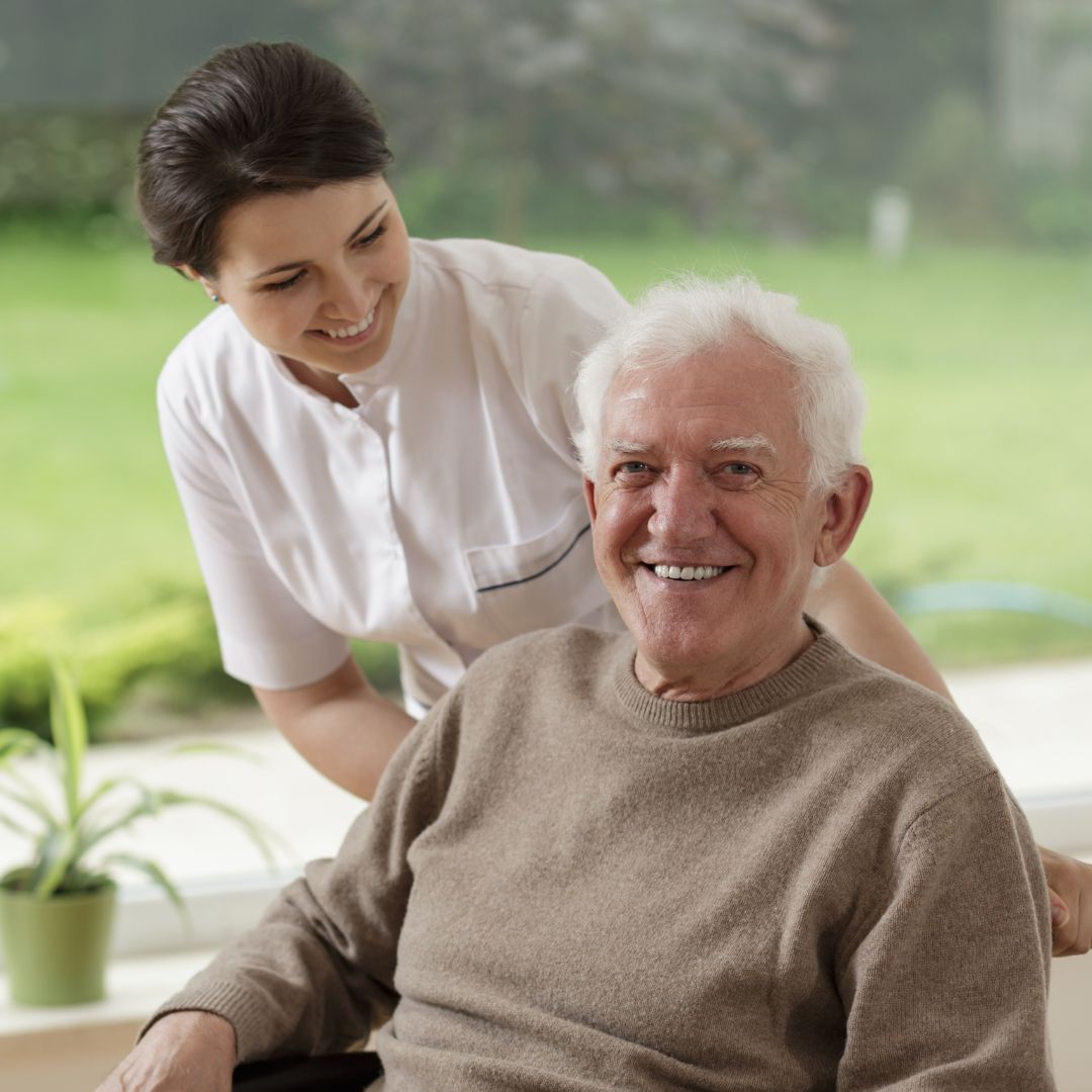 A female nurse helping an elderly man in a wheelchair.